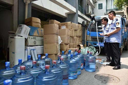 图说：执法人员现场查获百余桶假冒桶装水。